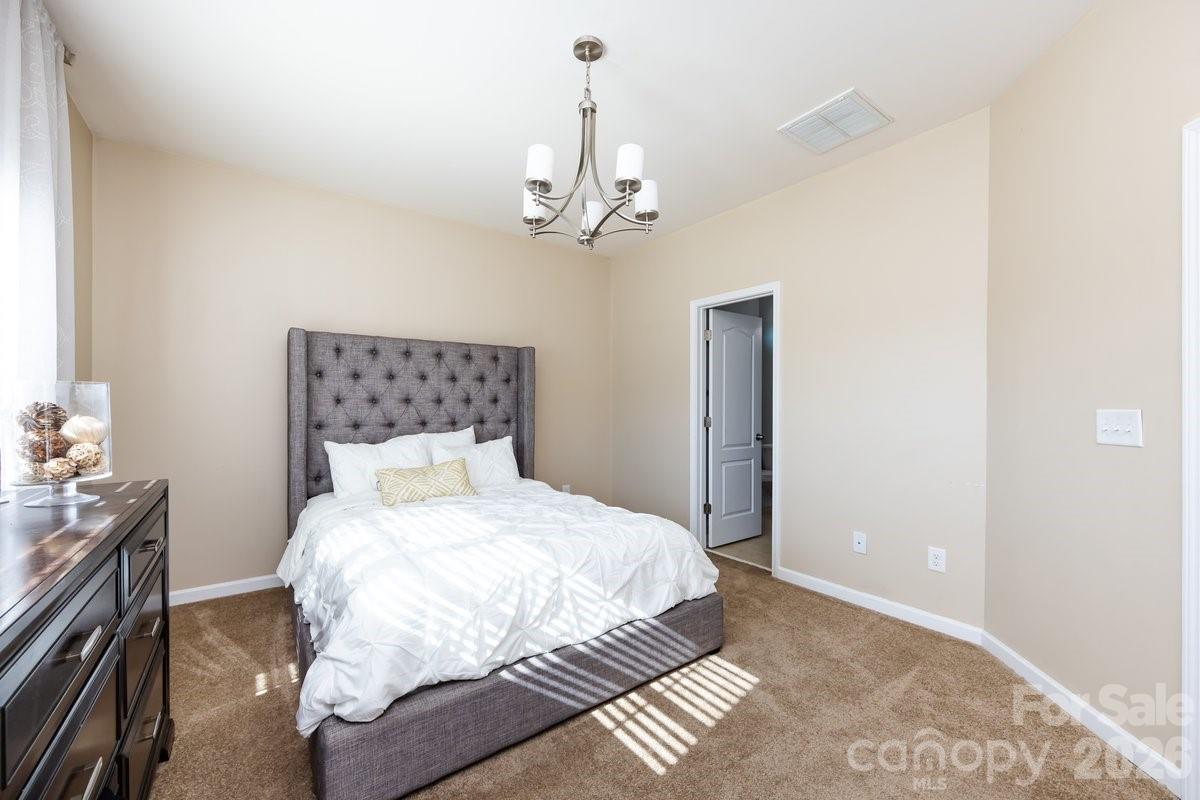 8931 Happiness Road Harrisburg, NC 28075 - Photo 13 of 27 a bedroom with a bed and a chandelier
