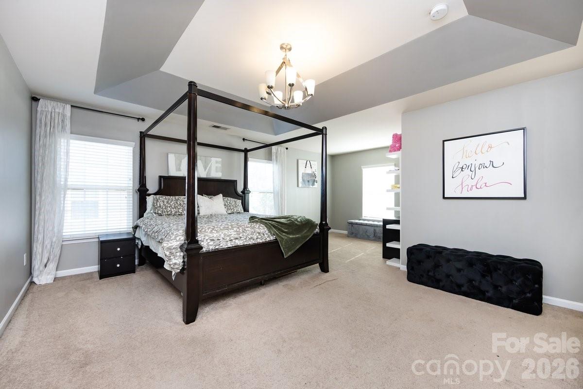 8931 Happiness Road Harrisburg, NC 28075 - Photo 18 of 27 a bedroom with bed and a chandelier