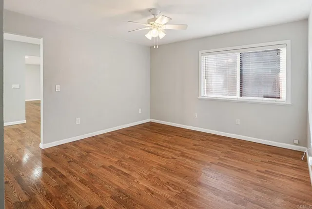 a view of empty room with wooden floor and fan