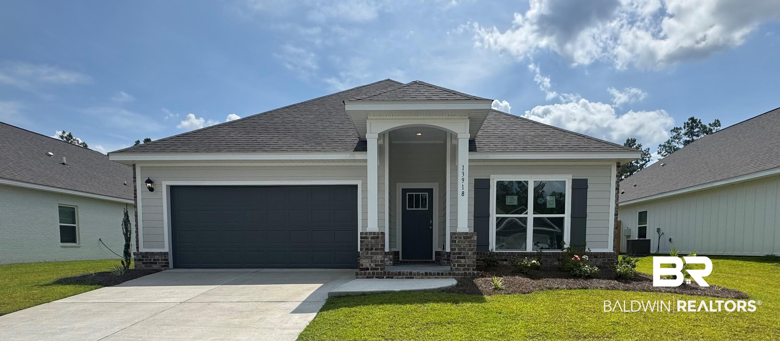 View of front of property with driveway, a garage, a front yard, roof with shingles, and stone siding