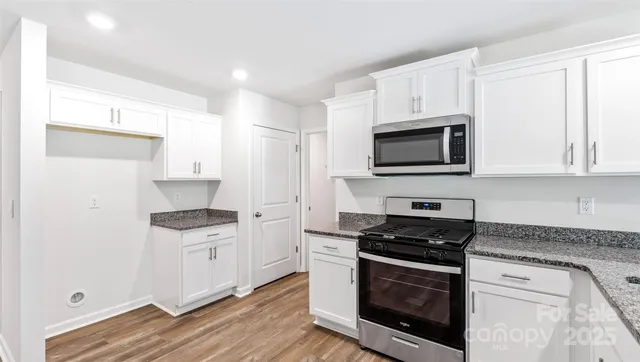 a kitchen with stainless steel appliances a white stove a microwave and a hard wood floors