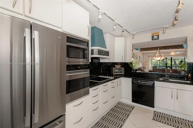 a kitchen with stainless steel appliances a refrigerator sink and white cabinets