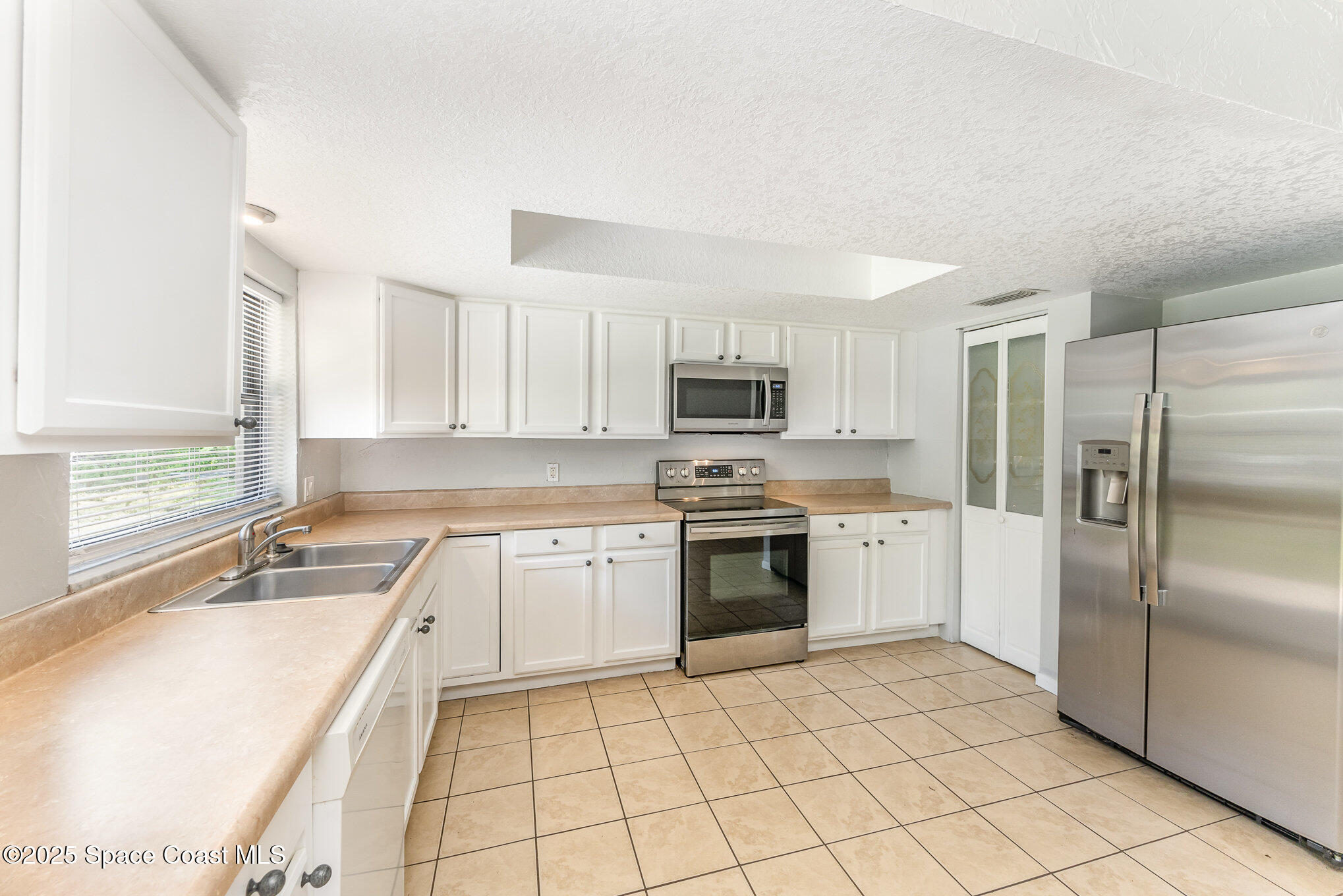 1981 Roc Rosa Drive Northeast Palm Bay, FL 32905 - Photo 9 of 29 a kitchen with a sink a refrigerator and white cabinets