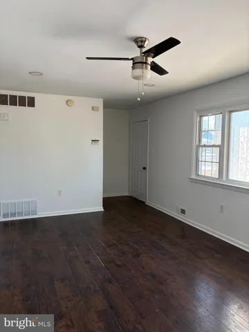an empty room with wooden floor fan and windows