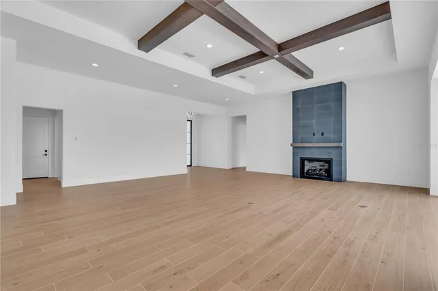 a view of an empty room with wooden floor and a ceiling fan