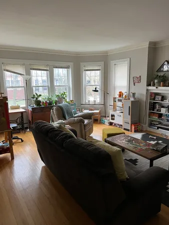 a living room with furniture hard wood floor and a window