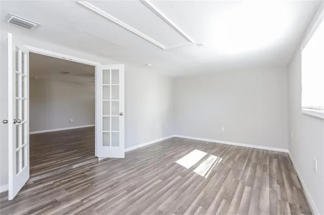 an empty room with wooden floor cabinet and windows