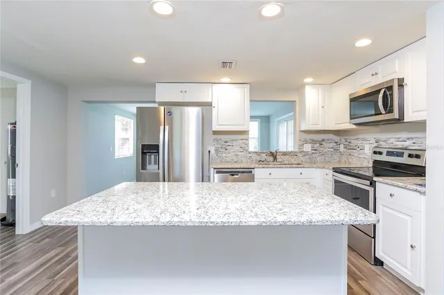 a kitchen with stainless steel appliances granite countertop a sink refrigerator and microwave