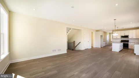 an empty room with wooden floor and a kitchen