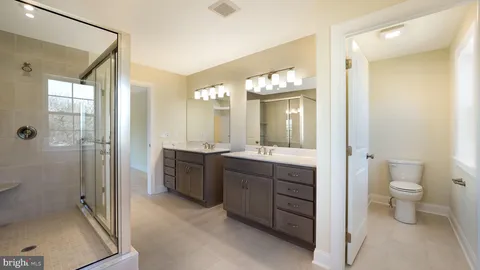 a spacious bathroom with a double vanity sink toilet and shower