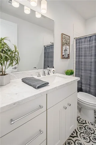 a bathroom with a granite countertop sink and a toilet