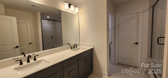 a bathroom with a double vanity sink a mirror and shower