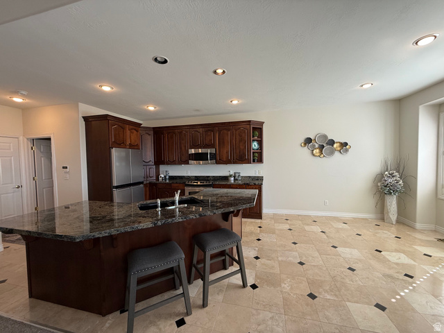 1562 Fairway Ridge Road Draper, UT 84020 - Photo 16 of 60 Spacious kitchen featuring dark wood cabinetry, stainless steel appliances, and a large island with a dark stone countertop and integrated sink
