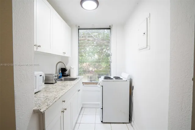 a kitchen with granite countertop cabinets stainless steel appliances a sink and a window