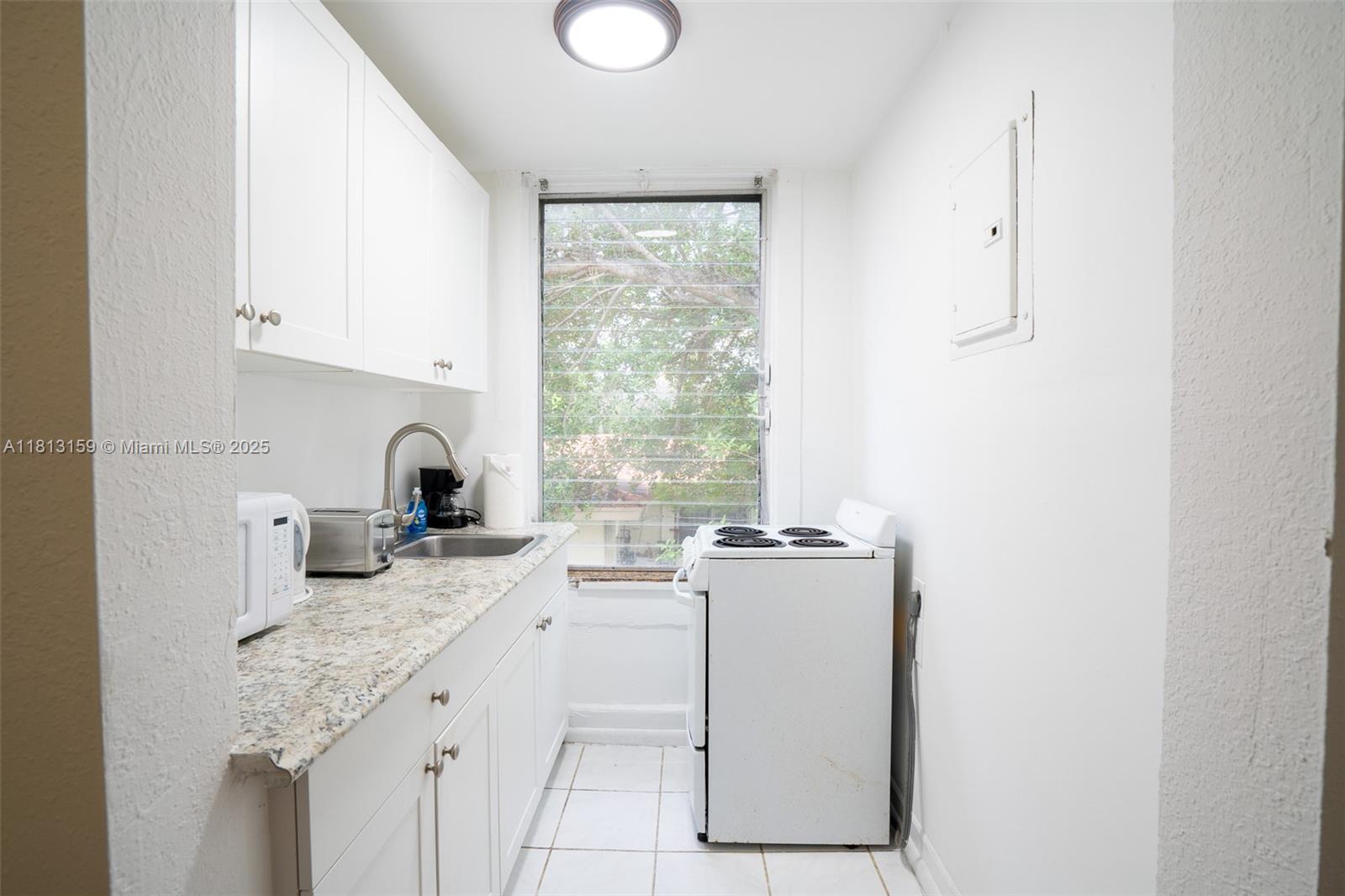 444 Ponce De Leon Boulevard, Unit 6 Coral Gables, FL 33134 - Photo 15 of 22 a kitchen with granite countertop cabinets stainless steel appliances a sink and a window