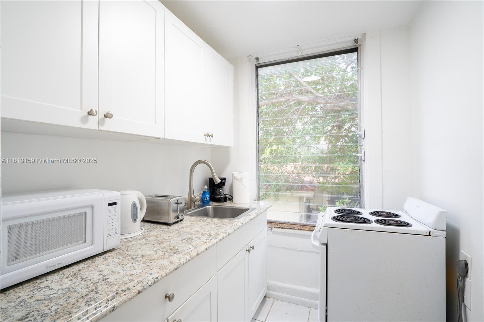 444 Ponce De Leon Boulevard, Unit 6 Coral Gables, FL 33134 - Photo 16 of 22 a kitchen with stainless steel appliances granite countertop a sink stove and white cabinets