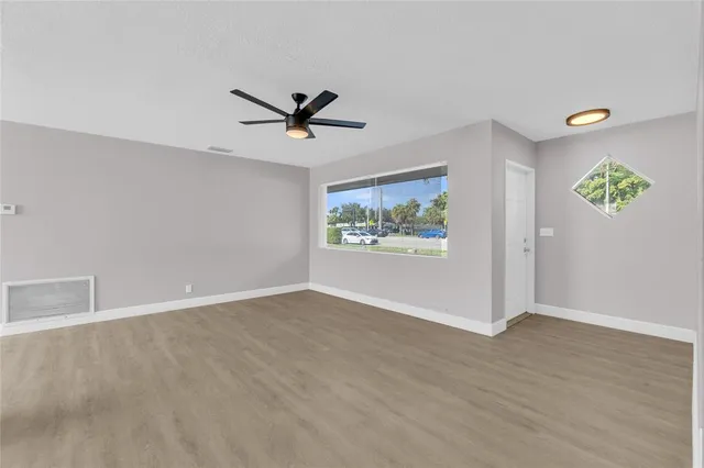 an empty room with wooden floor and windows