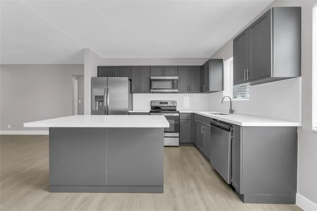 a kitchen with stainless steel appliances a sink a stove a refrigerator cabinets and a window