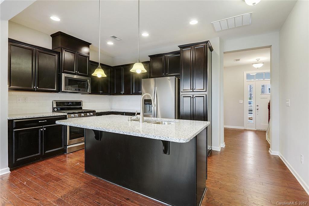1128 Roderick Drive, Unit 70 FALKNER B Fort Mill, SC 29708 - Photo 7 of 20 a large kitchen with stainless steel appliances kitchen island granite countertop a stove refrigerator and a sink