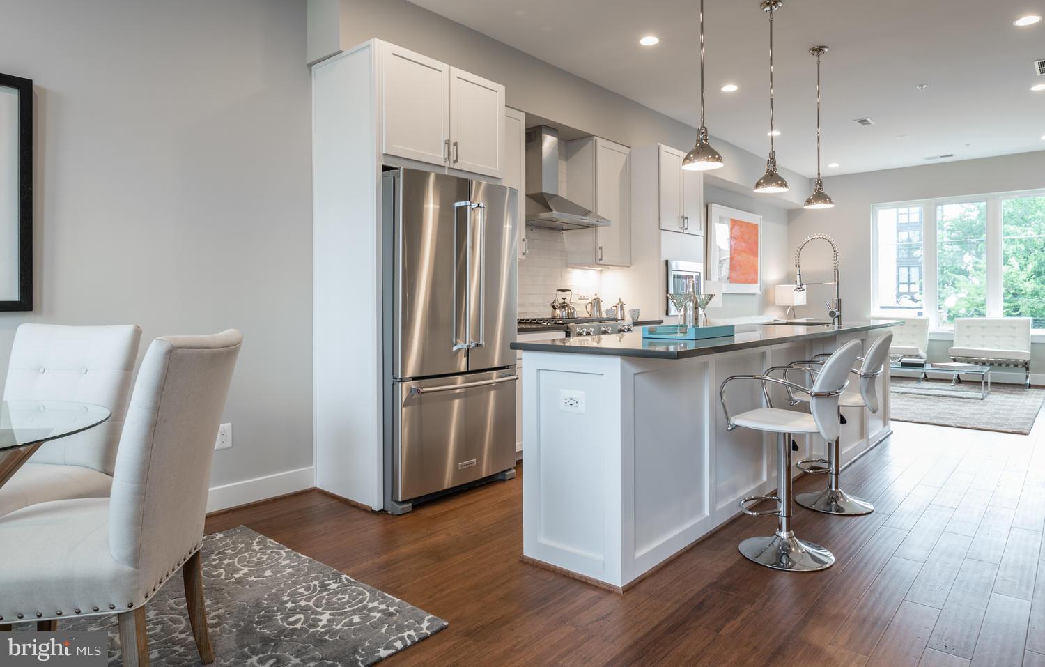 1007 Girard Street Northwest, Unit B Washington, DC 20001 - Photo 5 of 30 a kitchen with kitchen island stainless steel appliances a dining table chairs sink and wooden floor