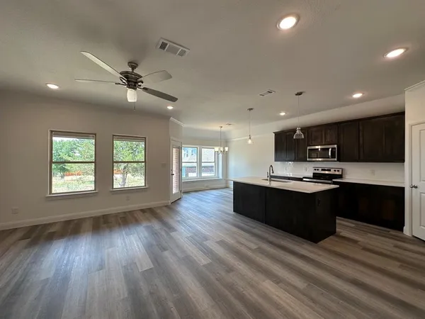 a living room with stainless steel appliances kitchen island granite countertop a stove top oven a sink with wooden floors
