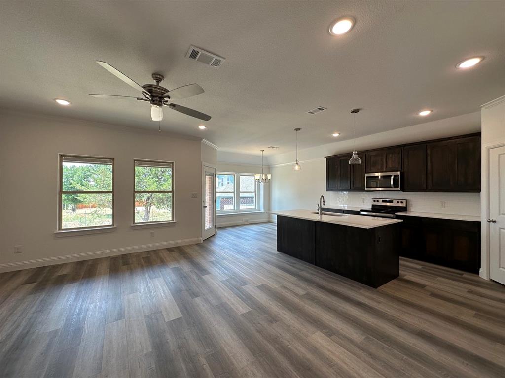 418 South 2nd Street Krum, TX 76249 - Photo 7 of 17 a living room with stainless steel appliances kitchen island granite countertop a stove top oven a sink with wooden floors