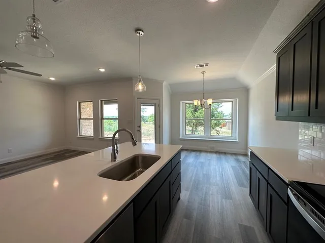 a kitchen with kitchen island granite countertop a sink window and wooden floor