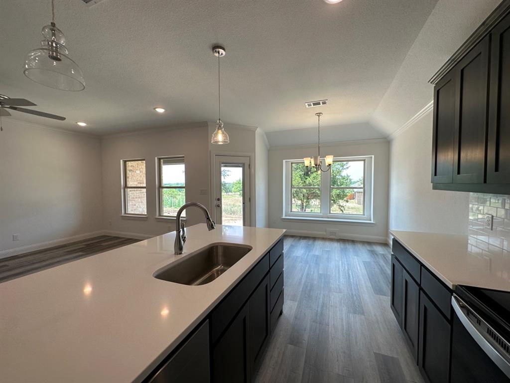418 South 2nd Street Krum, TX 76249 - Photo 9 of 17 a kitchen with kitchen island granite countertop a sink window and wooden floor
