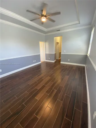 a view of empty room with wooden floor and fan