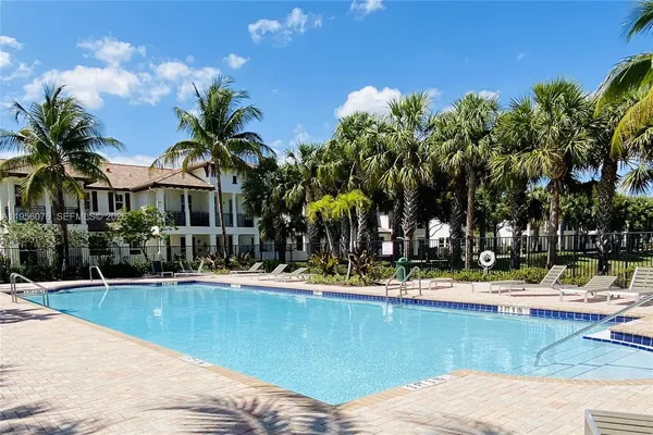 a view of a swimming pool with a lawn chairs and palm trees