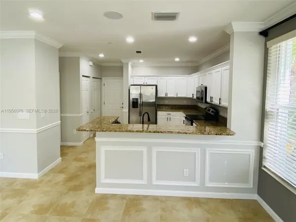 a kitchen with kitchen island white cabinets and refrigerator