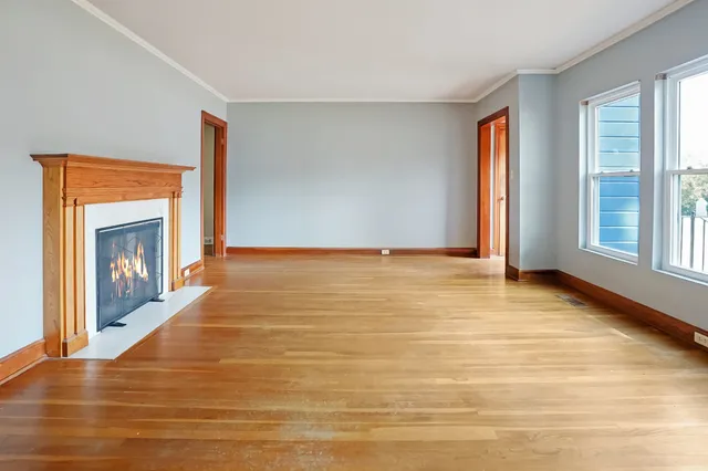 a view of an empty room with window and fire place