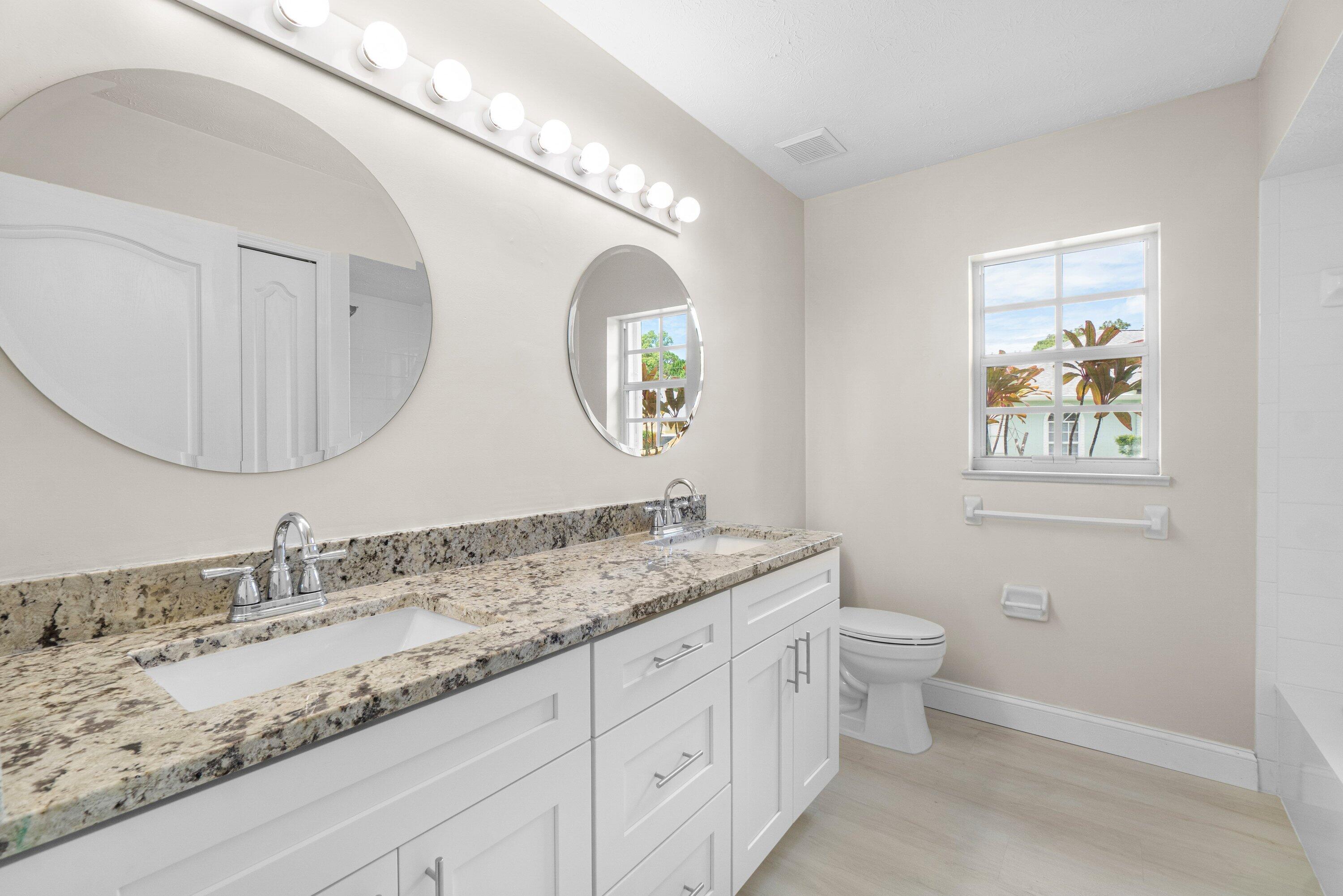 6807 Shelley Terrace Port St. Lucie, FL 34952 - Photo 20 of 34 a bathroom with a granite countertop toilet a sink and a mirror