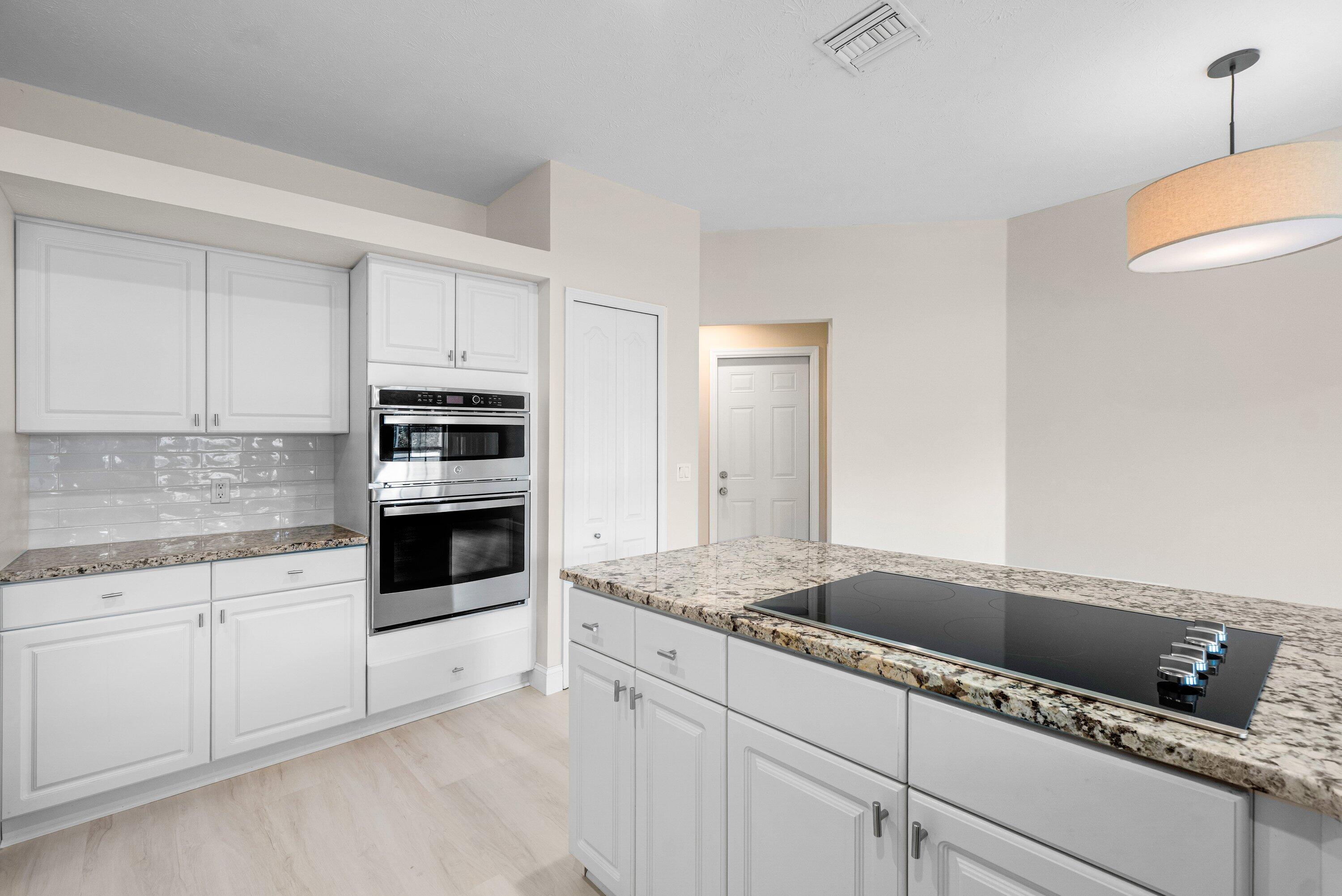 6807 Shelley Terrace Port St. Lucie, FL 34952 - Photo 9 of 34 a kitchen with granite countertop a sink and white cabinets