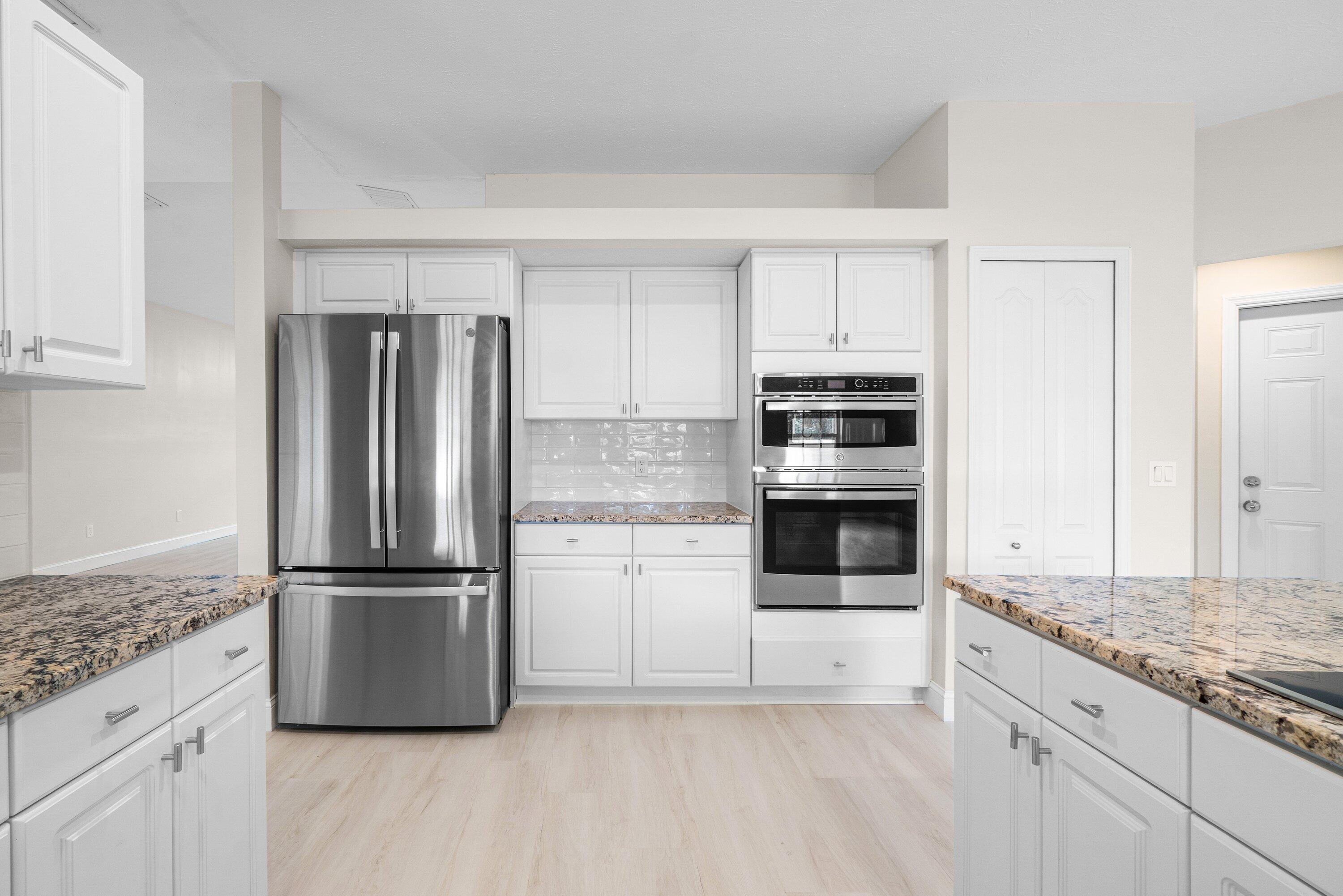 6807 Shelley Terrace Port St. Lucie, FL 34952 - Photo 10 of 34 a kitchen with granite countertop a refrigerator and a stove top oven