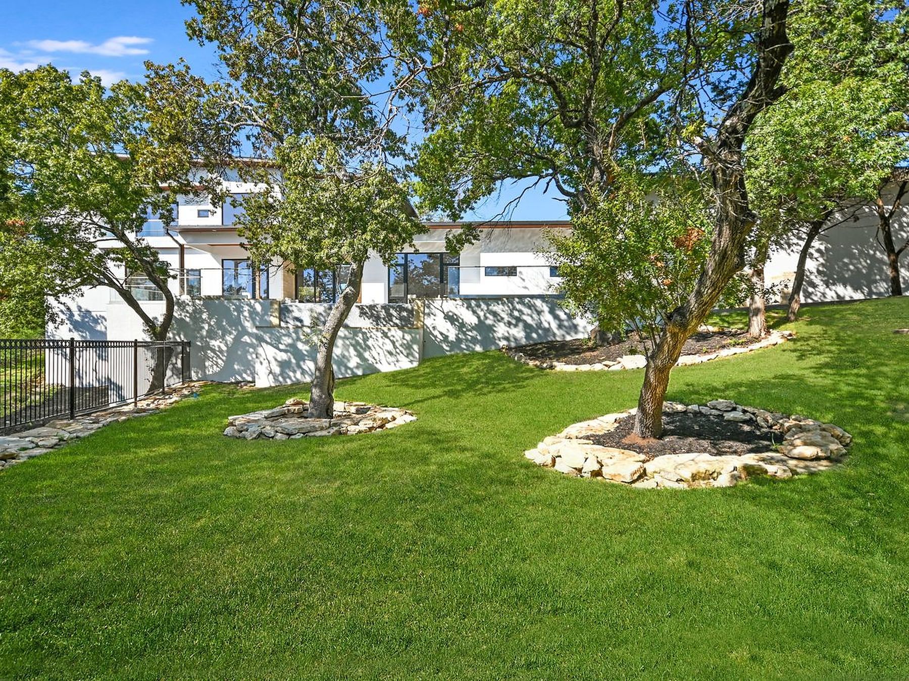 2476 Waymaker Way Austin, TX 78746 - Photo 28 of 31 A tiered landscape with verdant grass and mature trees defines this property's serene outdoor space.