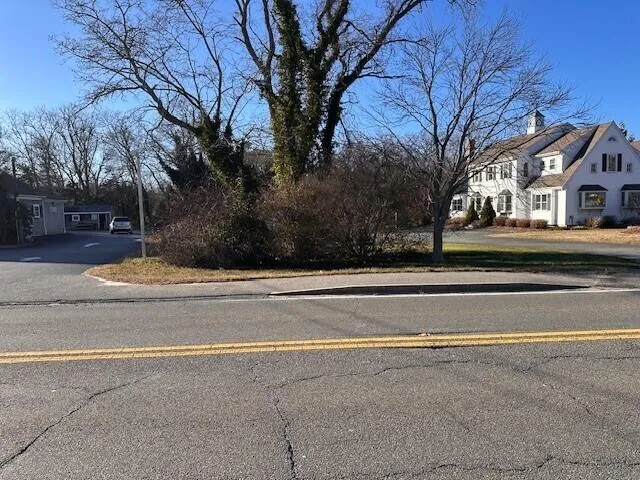a view of white house with a large space and large trees
