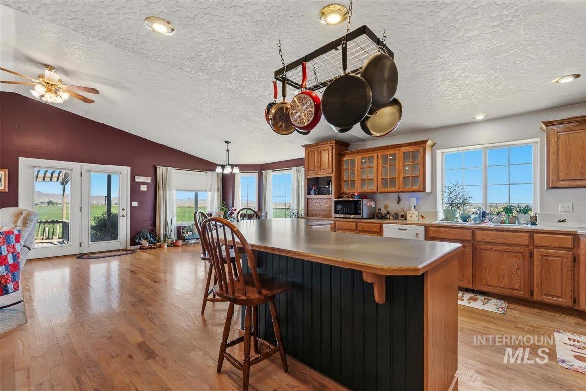 2331 Gulley Road Homedale, ID 83628 - Photo 11 of 46 Spacious kitchen with a central island featuring bar seating, wood-finish flooring, ample cabinetry with some glass-front doors, and large windows providing natural light