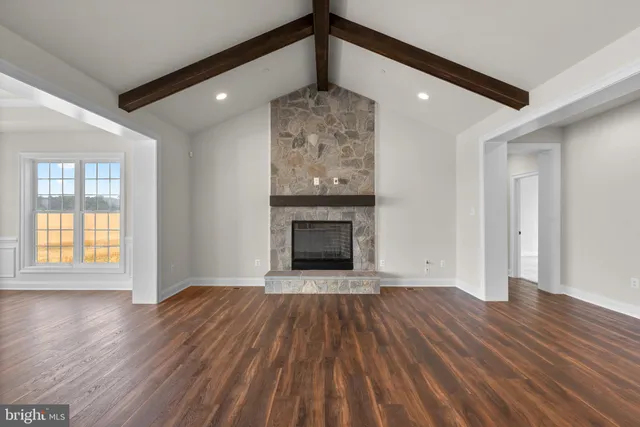 a view of an empty room with wooden floor fireplace and a window