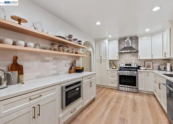 a kitchen with stainless steel appliances granite countertop a stove and white cabinets