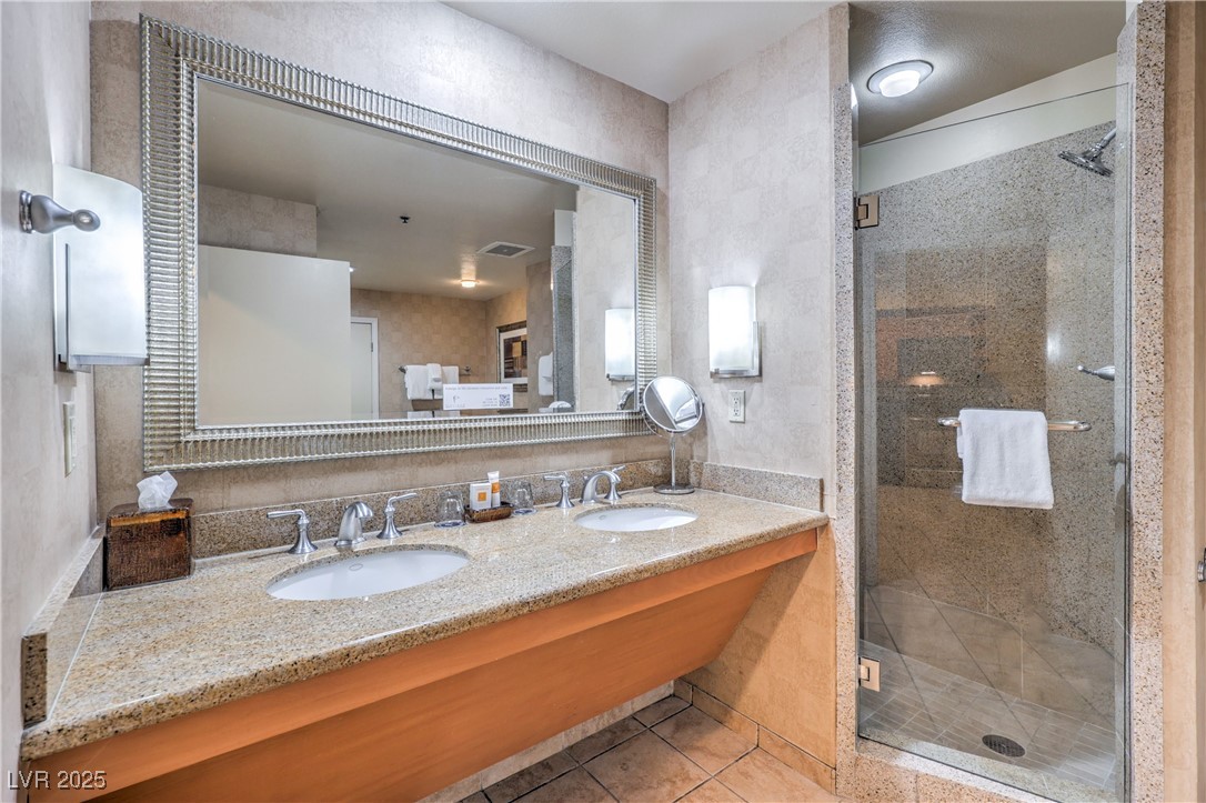211 East Flamingo Road, Unit 1505 Las Vegas, NV 89169 - Photo 21 of 45 Full bath with double vanity, light tile patterned flooring, a shower stall, and tile walls