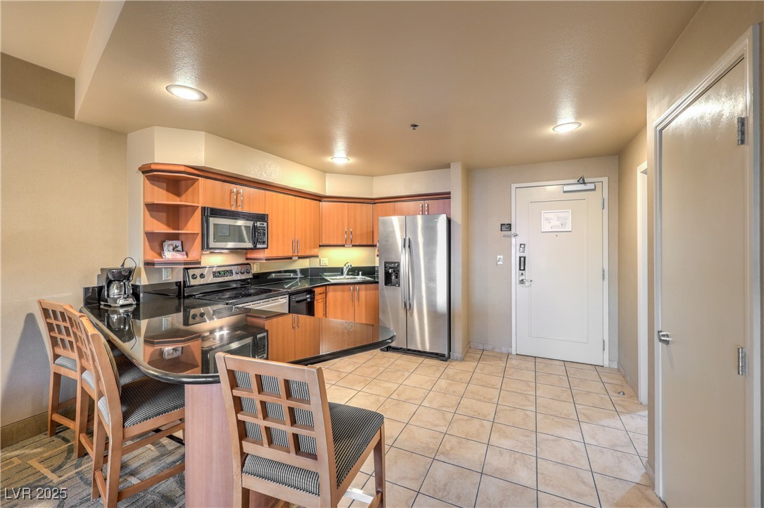 211 East Flamingo Road, Unit 1505 Las Vegas, NV 89169 - Photo 6 of 45 Kitchen featuring open shelves, stainless steel appliances, brown cabinetry, a peninsula, and a breakfast bar area