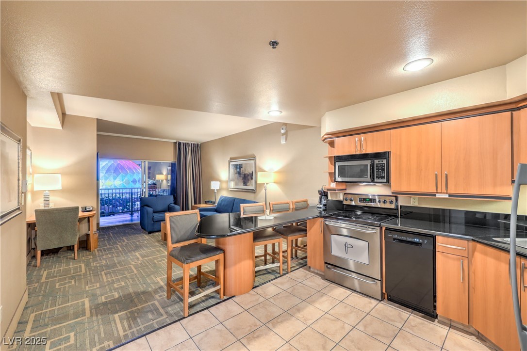 211 East Flamingo Road, Unit 1505 Las Vegas, NV 89169 - Photo 44 of 45 Kitchen featuring open floor plan, a kitchen bar, stainless steel appliances, a peninsula, and brown cabinetry