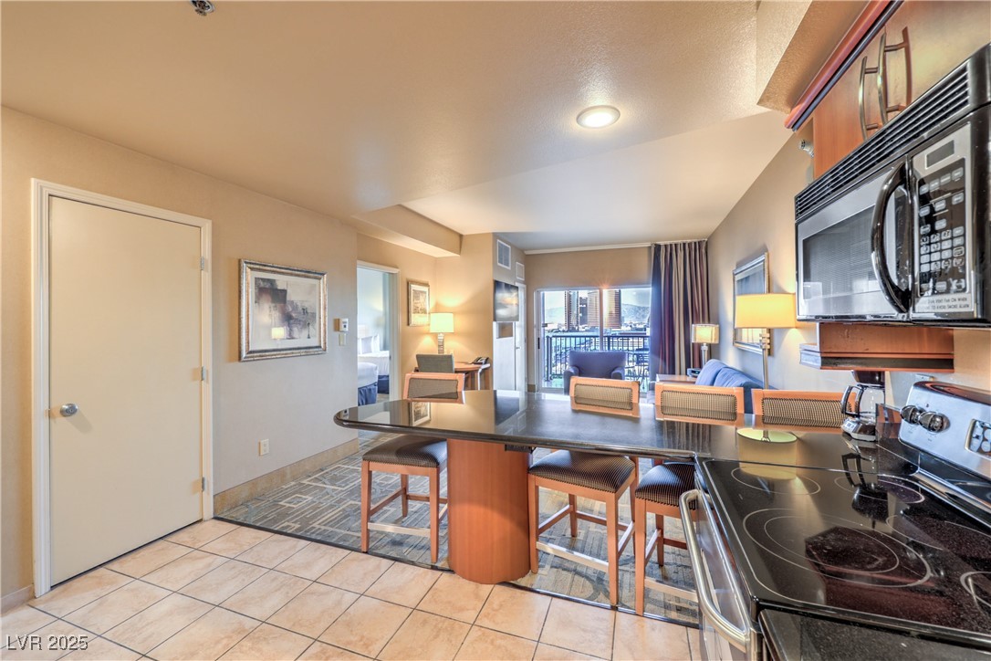 211 East Flamingo Road, Unit 1505 Las Vegas, NV 89169 - Photo 8 of 45 Kitchen featuring appliances with stainless steel finishes, a kitchen bar, dark countertops, brown cabinets, and a peninsula