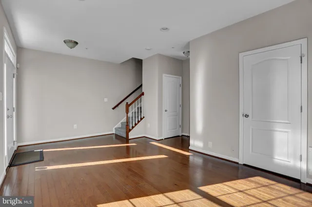 a view of a hallway with wooden floor and a bathroom