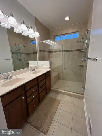 a bathroom with a double vanity sink mirror and shower