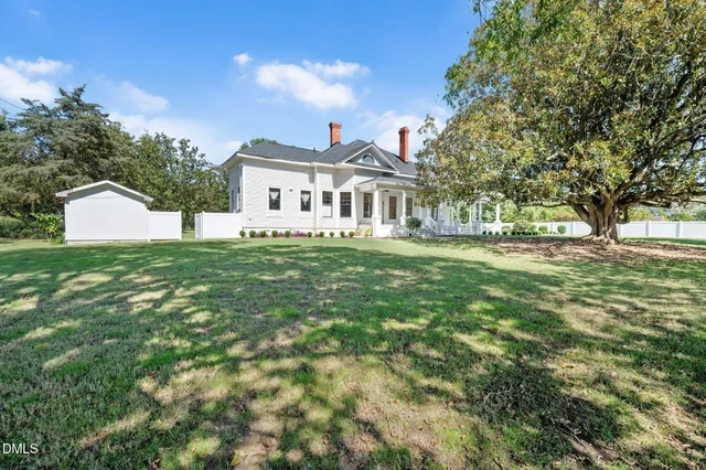 a view of a back yard of the house with a large tree