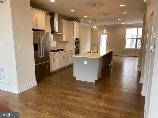 a kitchen with stainless steel appliances granite countertop a refrigerator a sink dishwasher a stove and a refrigerator with wooden floor