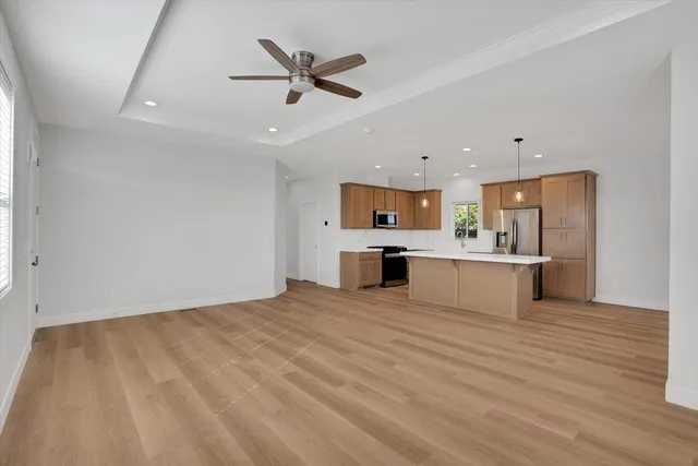 a large white kitchen with kitchen island a sink stainless steel appliances and cabinets