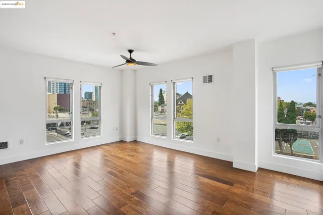 a view of an empty room with a window and wooden floor
